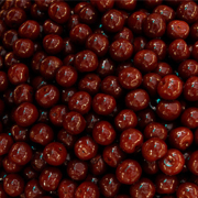 Gros plan sur une multitude de cerises confites brillantes, disposées en vrac, montrant leur texture lisse et leur glaçage sucré.